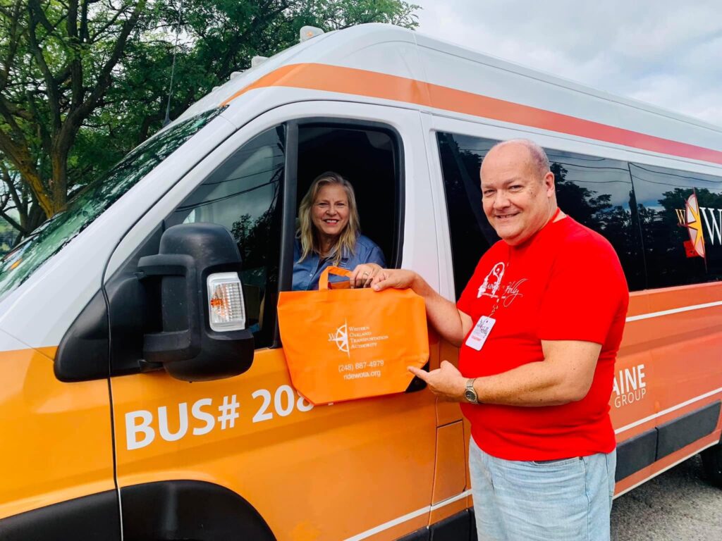 Man and woman exchanging bag by orange van