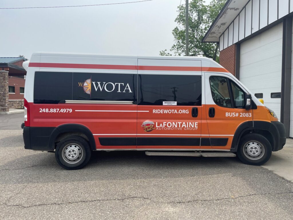 WOTA branded red and orange passenger van parked outdoors