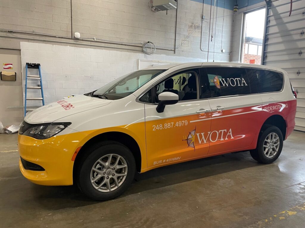 Colorful WOTA branded minivan in a garage